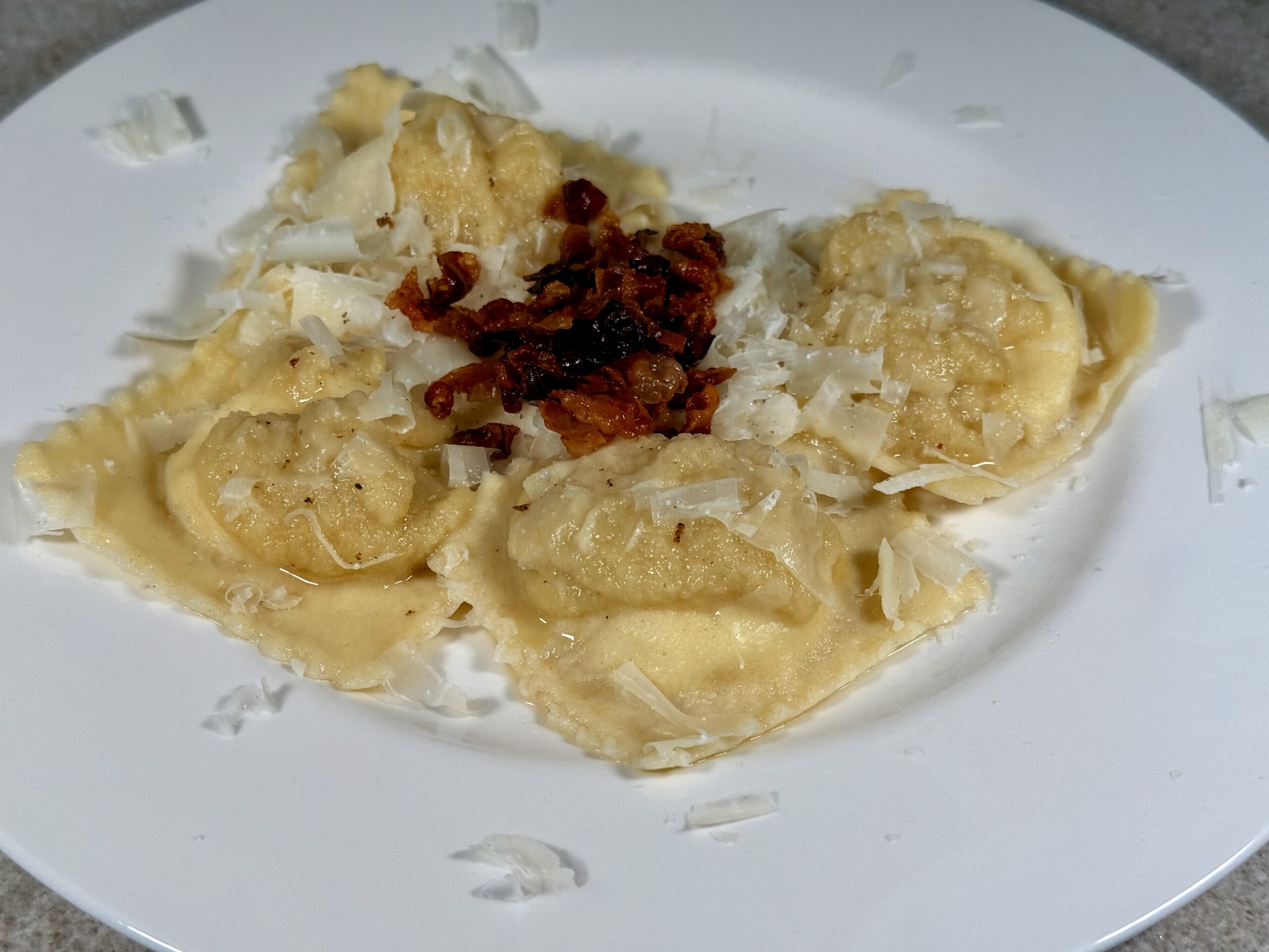 Ravioli filled with ricotta and pecorino cheese with onion cream and crispy pancetta | Carlo Florence chef