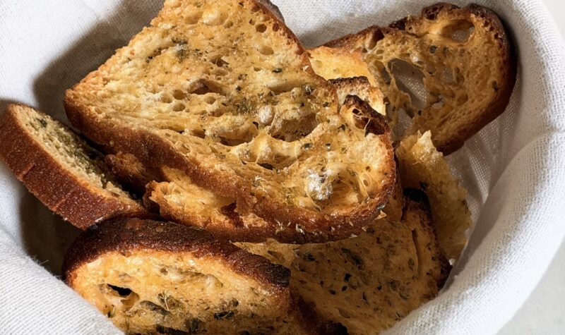 Crispy mini bruschetta with Sicilian oregano in a linen-lined bowl
