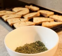 Bread slices ready to be seasoned, with crumbled Sicilian oregano